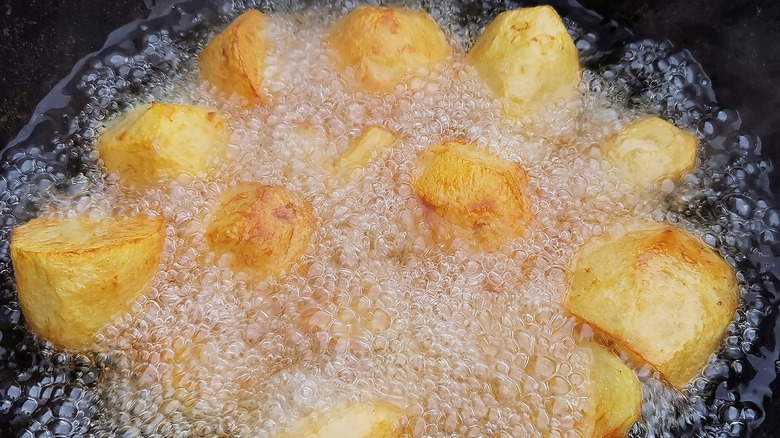 potatoes sizzling in skillet of oil