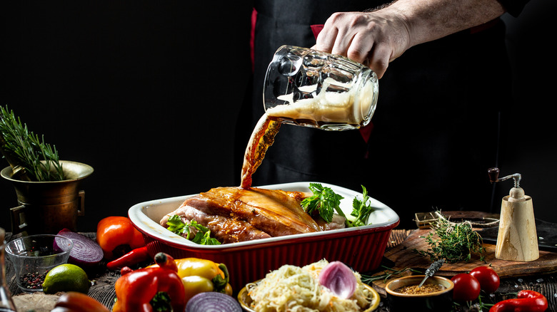 Beer being poured onto a roast with fresh vegetables surrounding