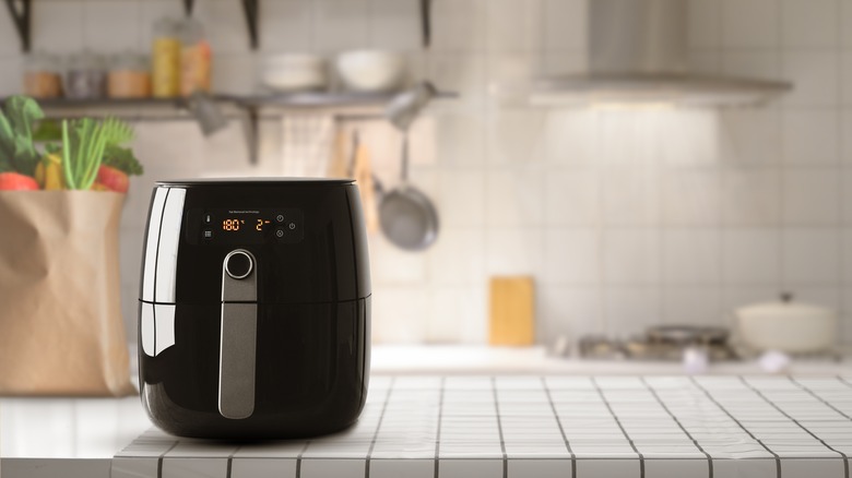 Black air fryer on white tile kitchen counter