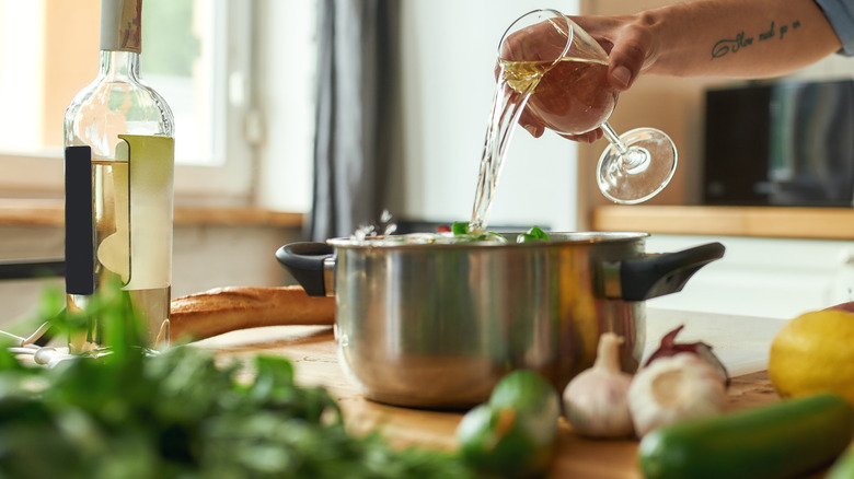 pouring wine into pan of sauce