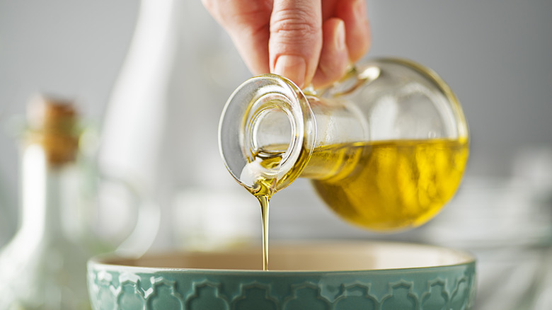 Hand pouring olive oil into a bowl