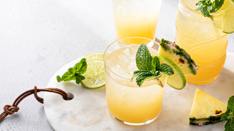 Two mai tai cocktails with lime slices and pineapple wedges