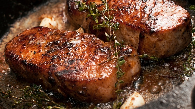 Glazed homemade pork chops searing in a cast iron skillet