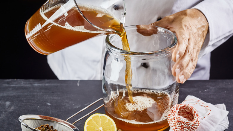 pouring tea into glass vessel