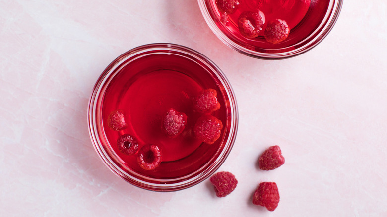 Ramekins of raspberry syrup with raspberries floating in it