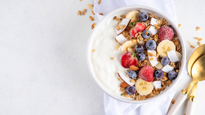 A bowl of yogurt with granola, berries and coconut flakes