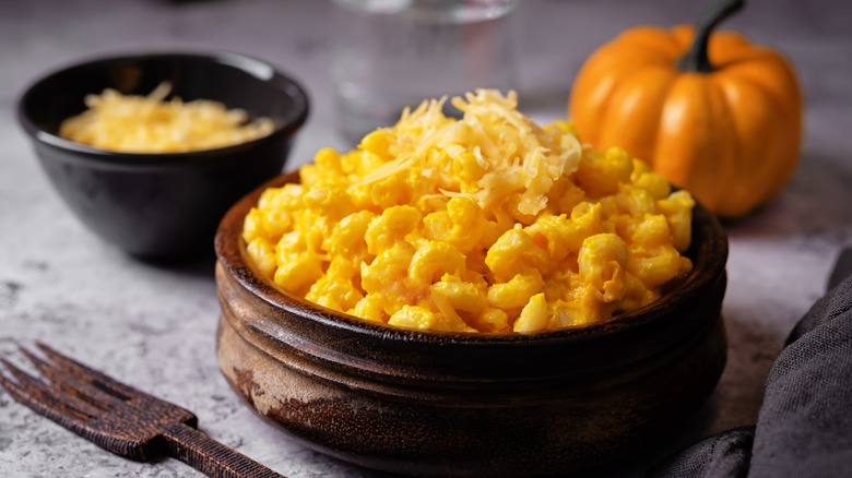 A bowl of pumpkin mac and cheese with a pumpkin