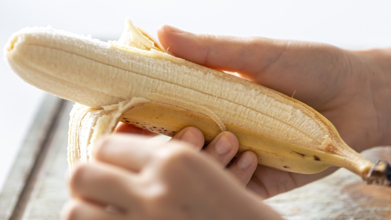 Hands peeling a banana