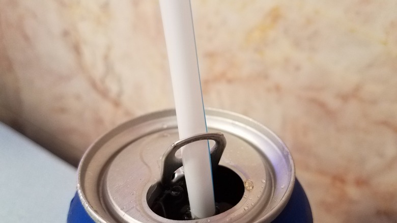 soda can with straw through the tab