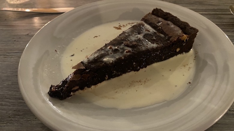 slice of brownie in cream on a white plate