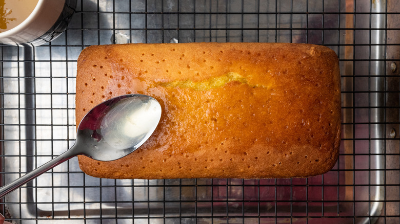 spooning lemon syrup into a lemon cake