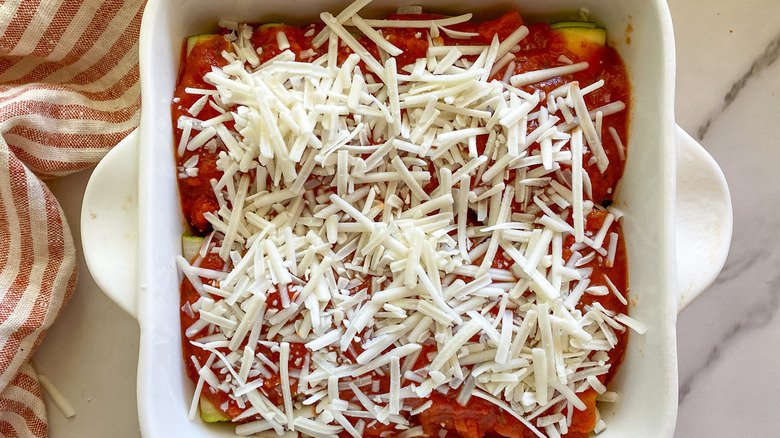 roll-ups in baking dish topped with cheese